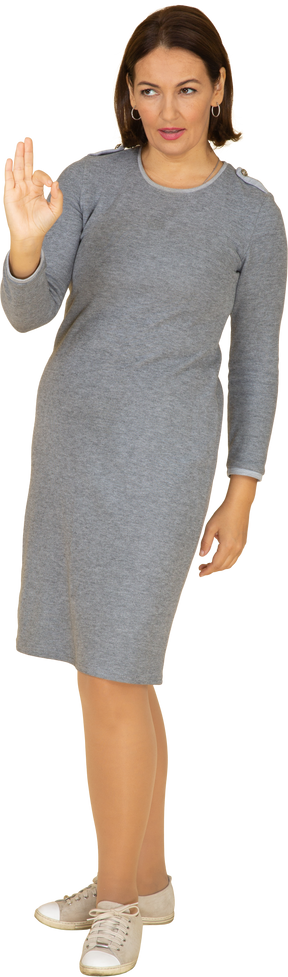 Front view of a woman in grey dress showing ok sign