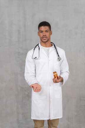 Молодой врач-мужчина держит таблетку