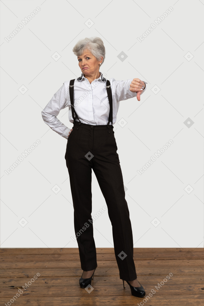 Front view of an old displeased female in office clothes showing a thumb down