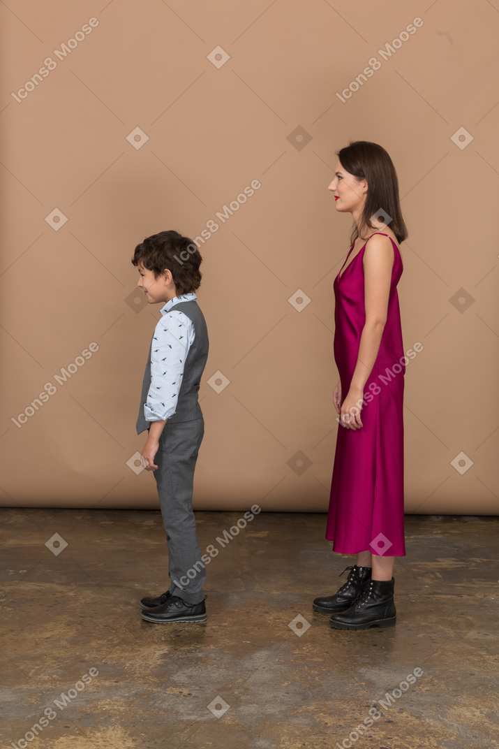 Mujer en vestido rojo y niño de pie en el perfil
