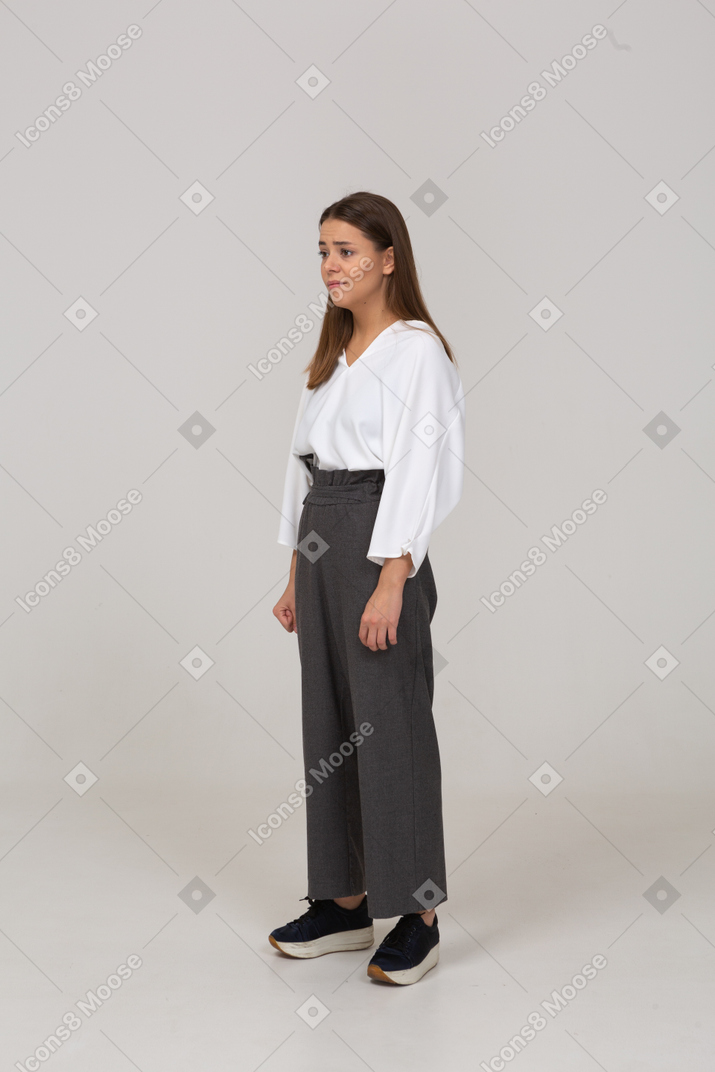 Three-quarter view of an upset young lady in office clothing clenching fists