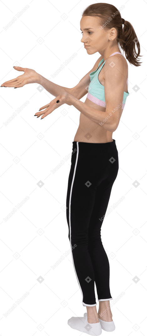 Vista posterior de tres cuartos de una perpleja jovencita en ropa deportiva extendiendo las manos