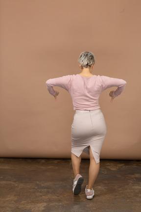 Vista posteriore di una donna in abiti casual che mostra i pollici in giù