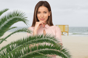 A woman standing on a beach next to a palm tree