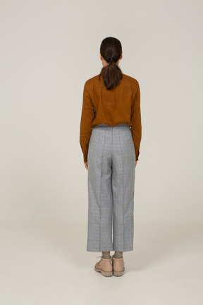 Back view of a young asian female in breeches and blouse standing still