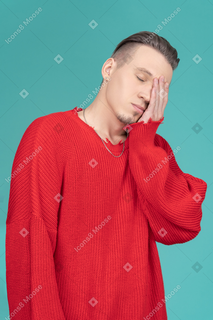 Sleepy young man in red sweater