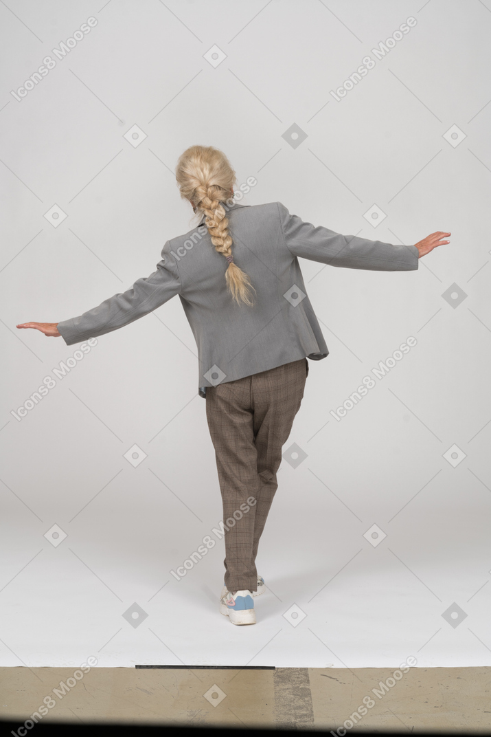 Rear view of an old lady in suit posing with outstretched arms