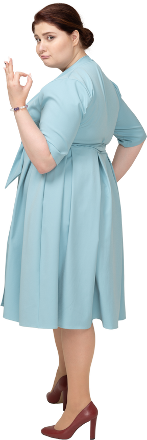 Вид сбоку женщины в синем платье показывает знак ок