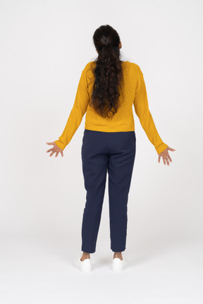 Вид сзади девушки в одежде казуа, стоящей с протянутыми руками
