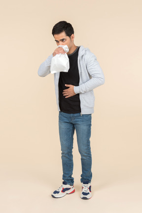 Young caucasian man breathing into a paper bag