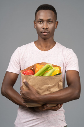 Un joven sosteniendo una bolsa de supermercado