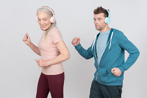Anciana y chico joven usando auriculares y corriendo