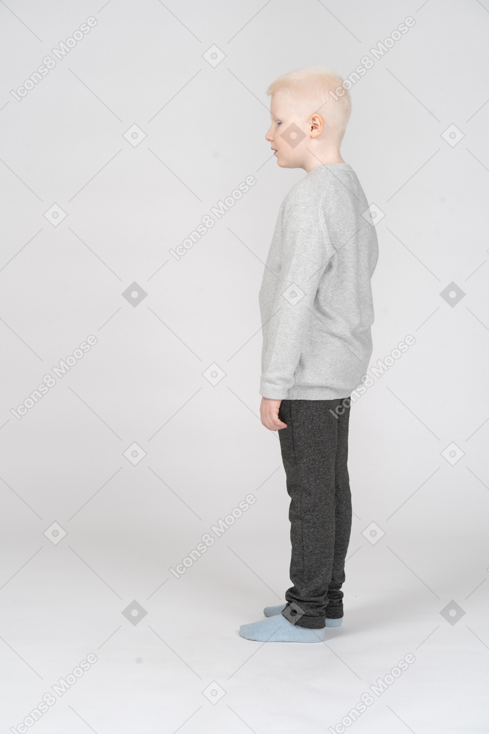 Side view of a kid boy standing still and looking aside