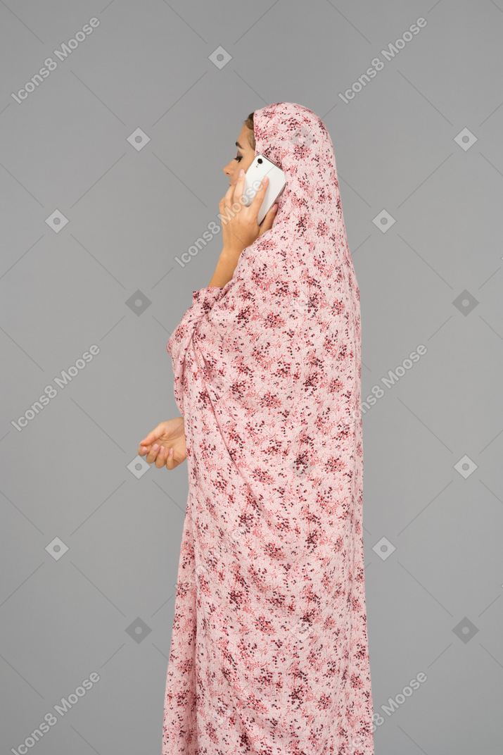 Mulher em um vestido de oração falando ao telefone