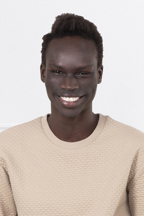 A young man in a tan sweater smiling