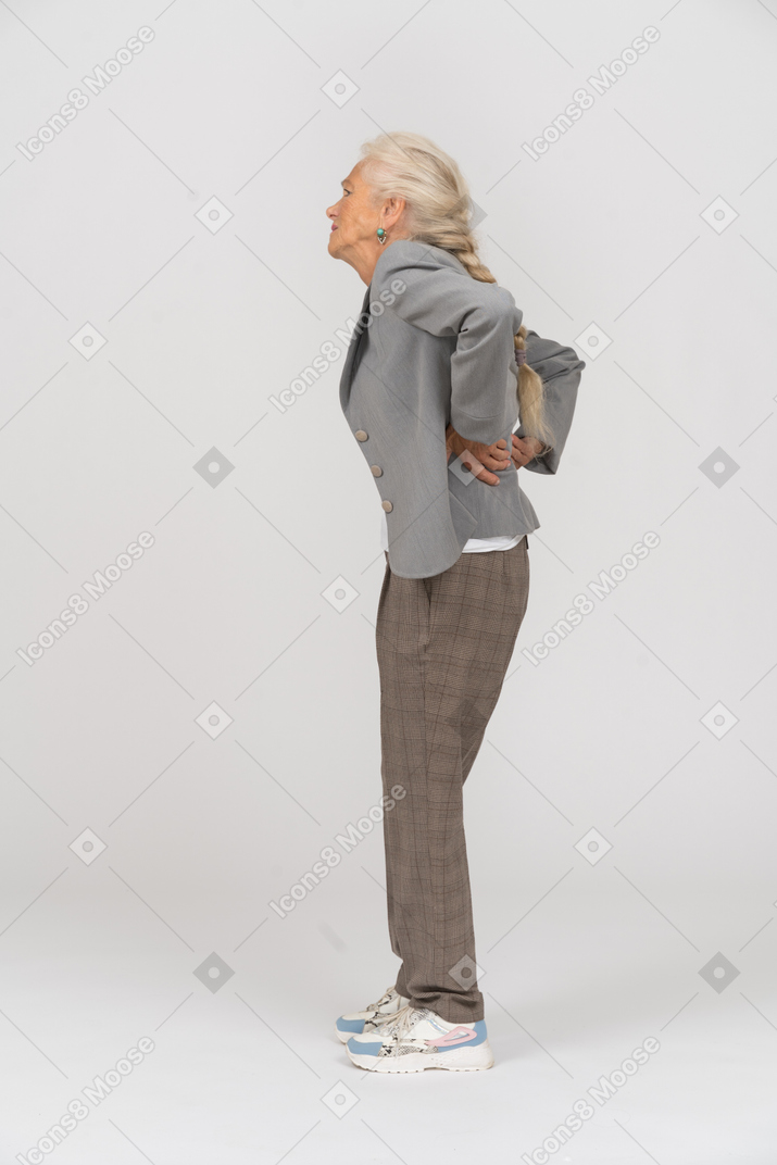 Vista lateral de uma senhora idosa de terno sofrendo de dores nas costas