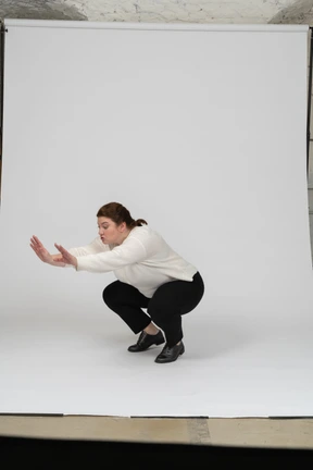 Side view of a plump woman in casual clothes squatting