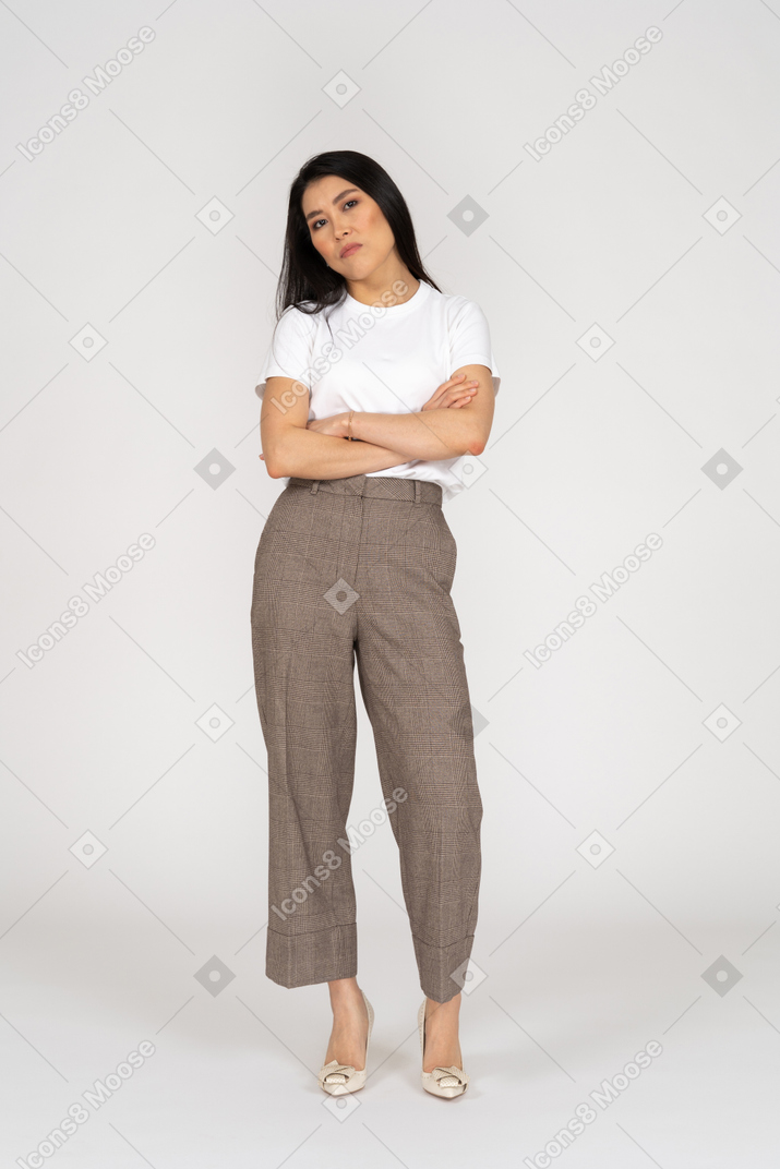 Front view of a suspicious young lady in breeches and t-shirt crossing hands tilting head