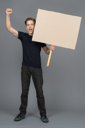 Joven excitado gesticulando y sosteniendo un cartel