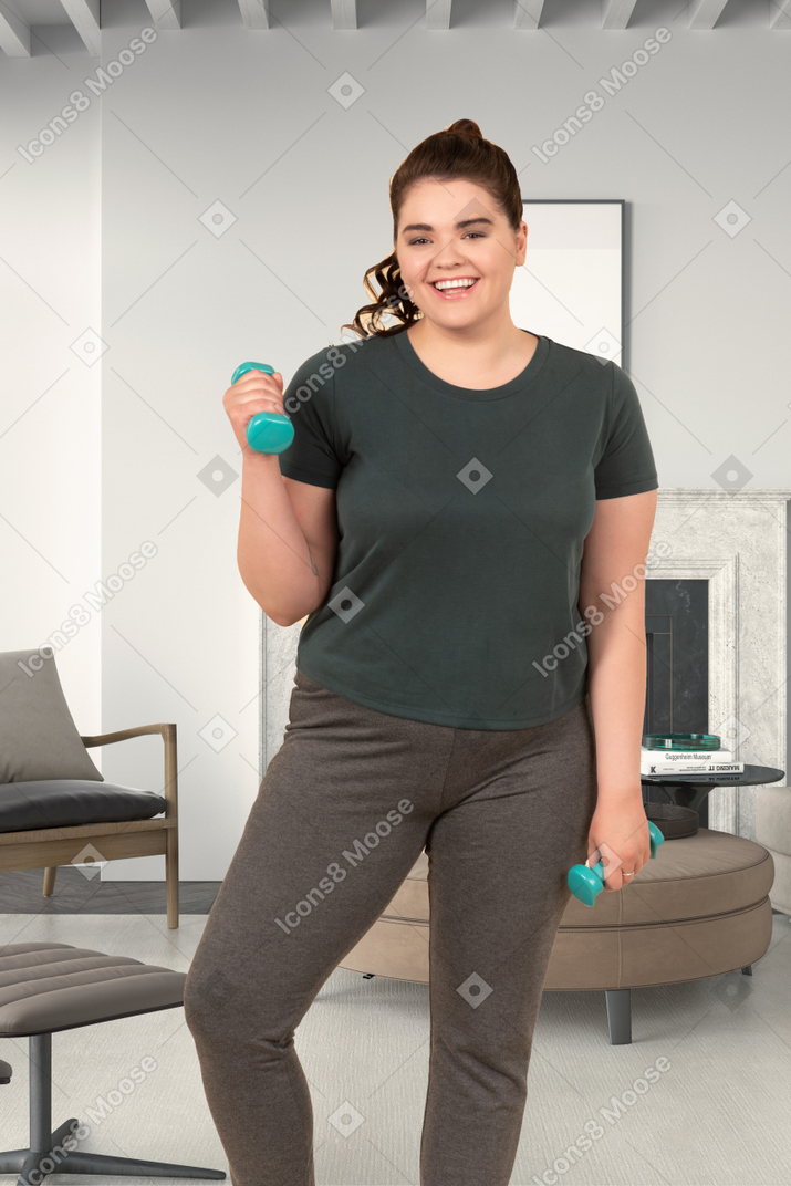 A smiling woman holding two dumbbells
