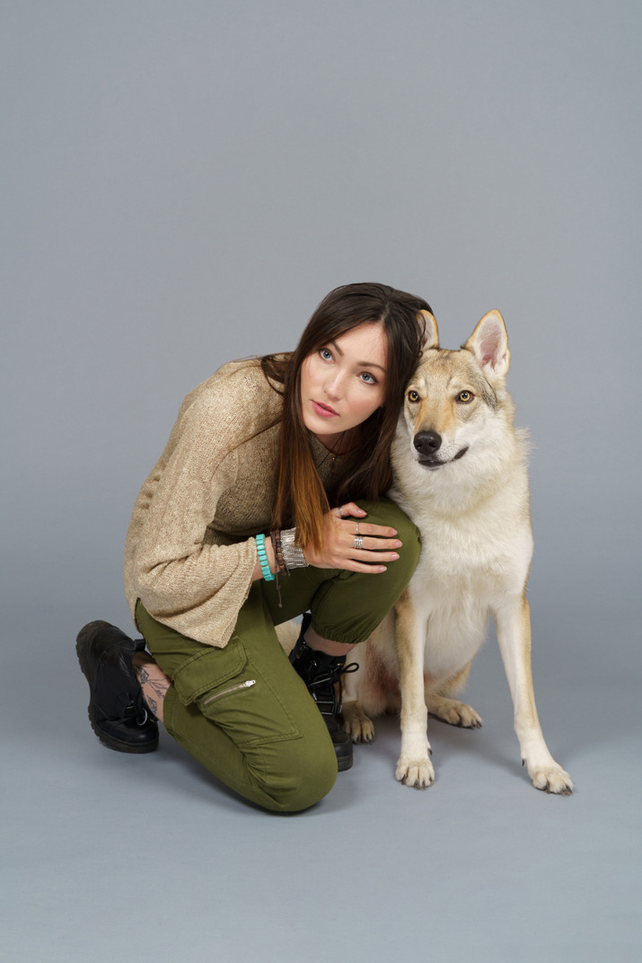 彼女の犬のそばに座っている女性マスターのフルレングス のフォト