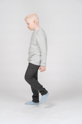 Side view of a little boy walking and looking down