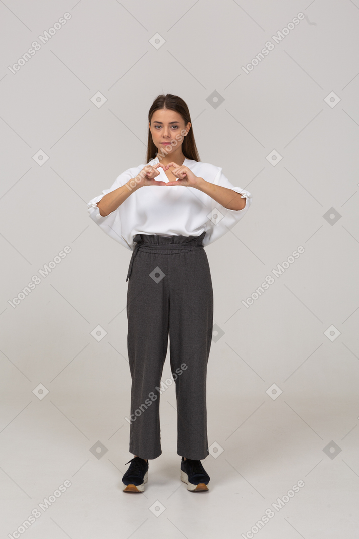 Front view of a young lady in office clothing showing heart gesture