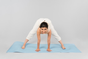 Jeune femme indienne debout dans pose sur tapis de yoga