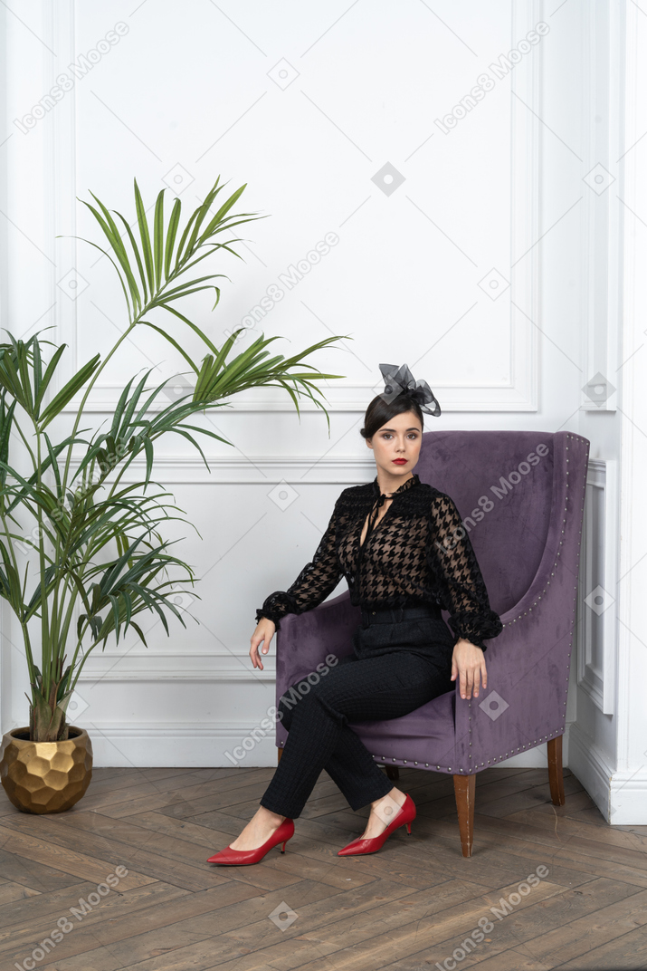 A woman sitting on a purple chair next to a potted plant