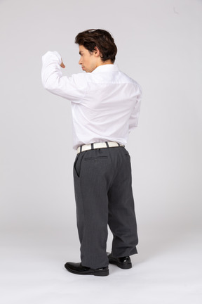 Vista traseira de um trabalhador de escritório flexionando os músculos do braço