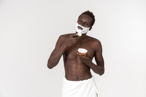 Ein junger schwarzer mann mit einem weißen badetuch um die taille macht seine morgenroutine