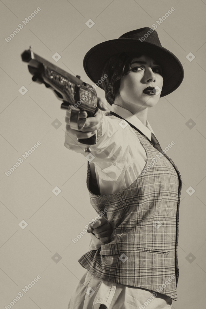 Confident woman in hat aiming the gun with one hand