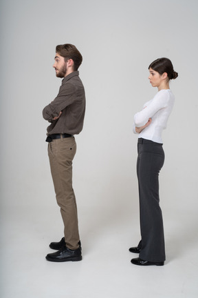 Vista lateral de um jovem casal com roupas de escritório, cruzando os braços