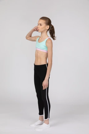 Three-quarter view of a teen girl in sportswear touching head