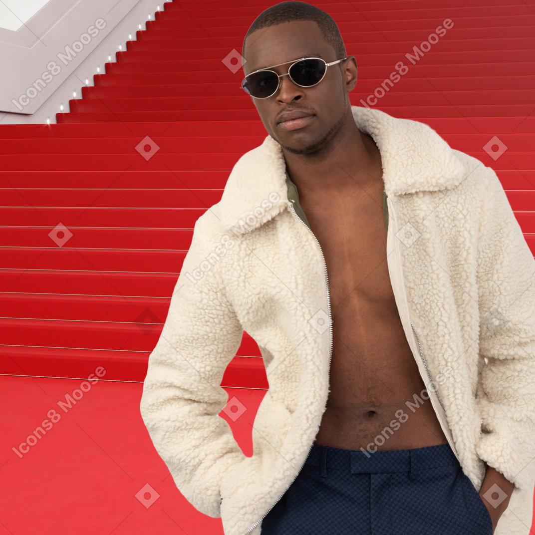 A man in a white coat posing on a red carpet