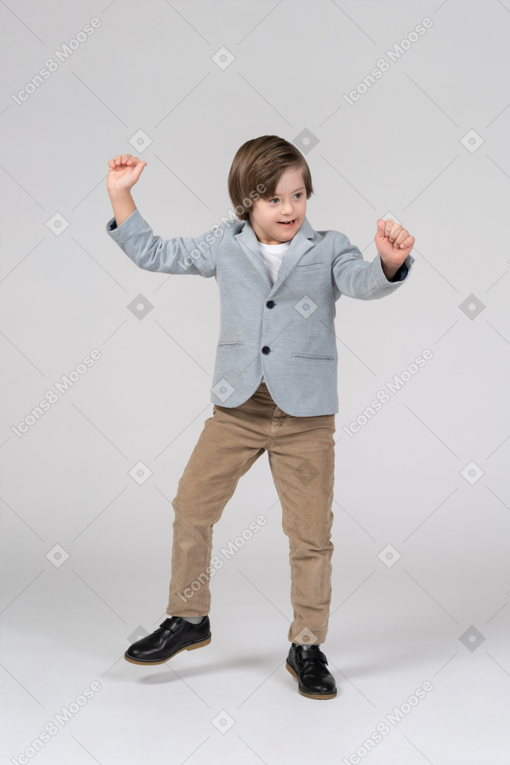 Menino feliz em um blazer dançando