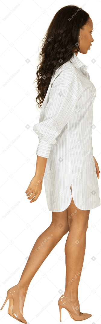 Vista posteriore di tre quarti di una giovane donna dalla carnagione scura in abito bianco