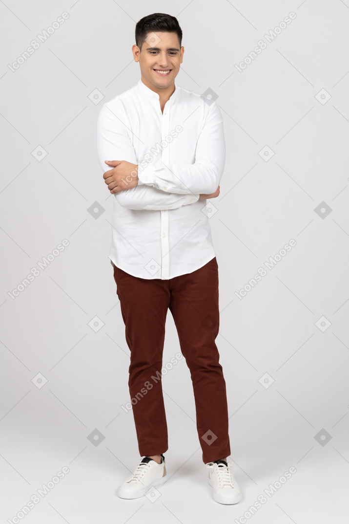 Vista frontal de un joven latino sosteniendo sus codos y sonriendo