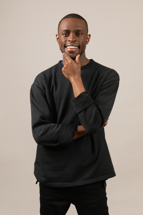 Smiling young man touching chin