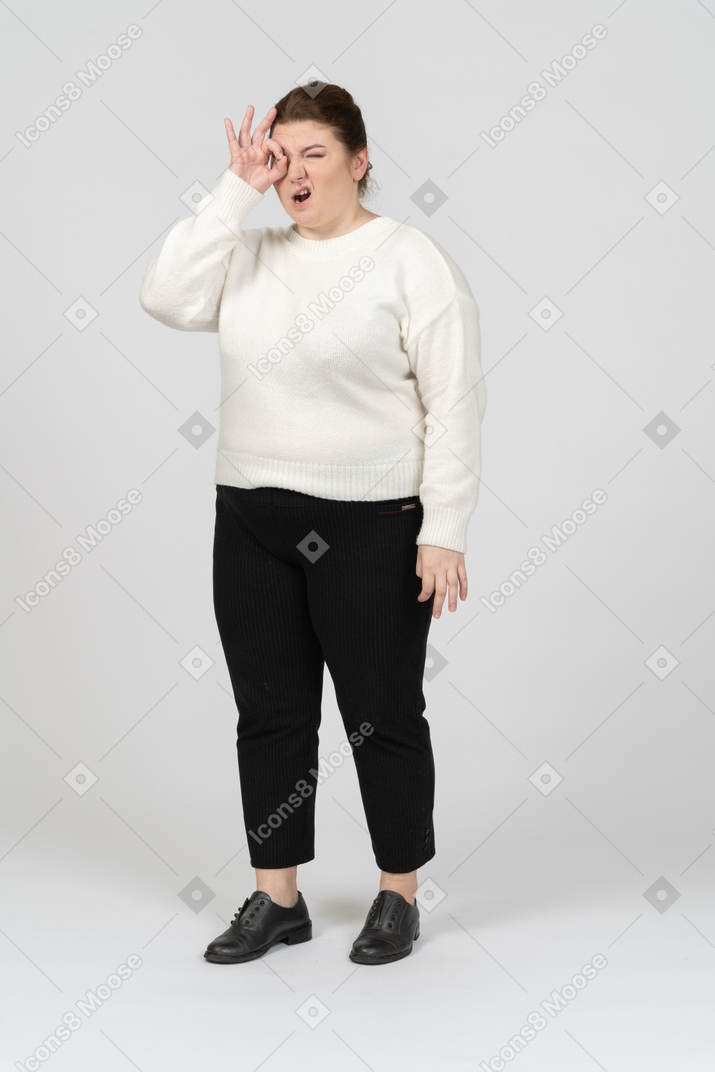 Femme de taille plus dans des vêtements décontractés regardant à travers les doigts