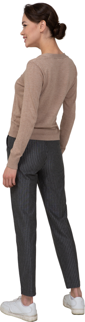 Три четверти сзади улыбающейся женщины в пуловере и брюках
