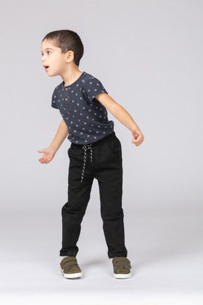 Vista frontal de um garoto emocional em roupas casuais em pé com os braços estendidos