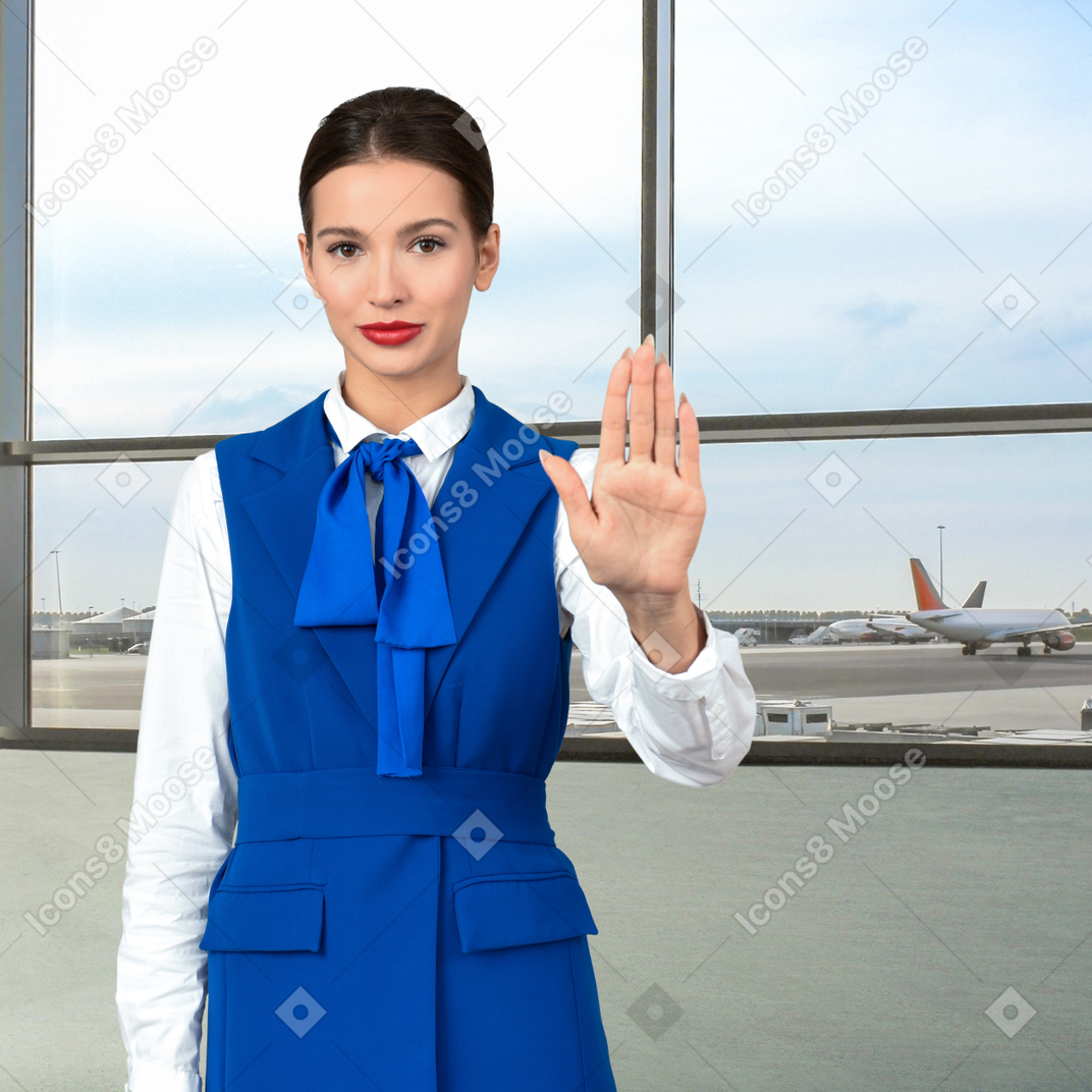 A female flight attendant showing stop hand gesture in an airport