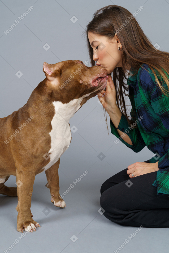 Nahaufnahme eine frau, die sitzt und ihre braune bulldogge küsst
