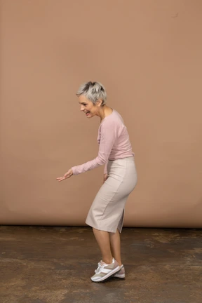 Side view of a woman in casual clothes making welcoming gesture