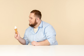 Grande homem sentado à mesa e segurando sorvete