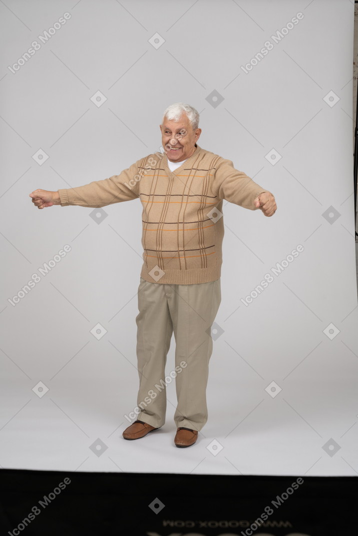 伸ばした腕で立っているカジュアルな服装で幸せな老人の正面図