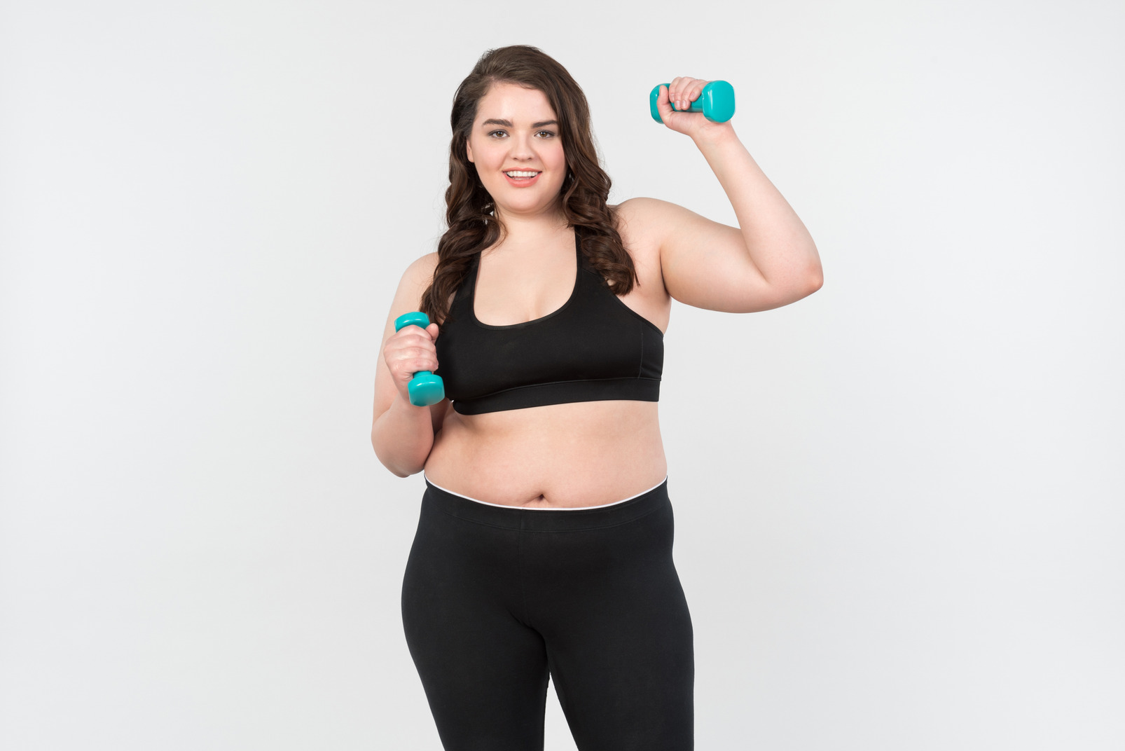 Young plus-size model in sportswear holding hand weights
