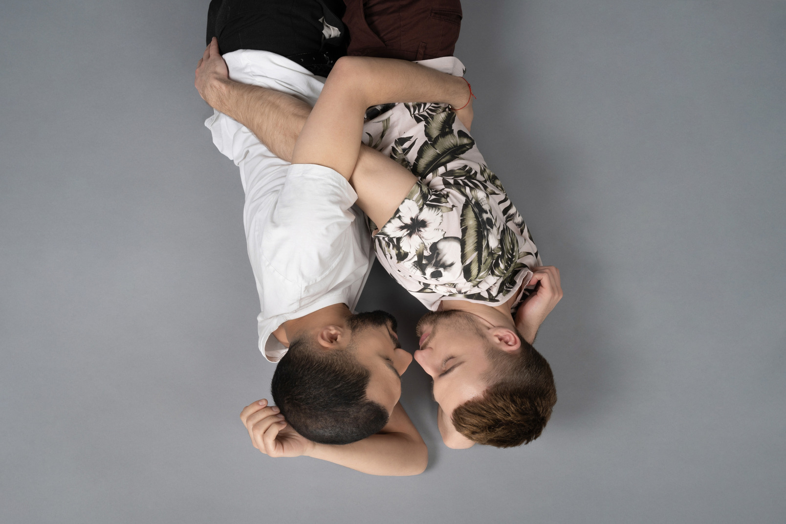 Flat lay of two young men lying on the floor on their sides and hugging