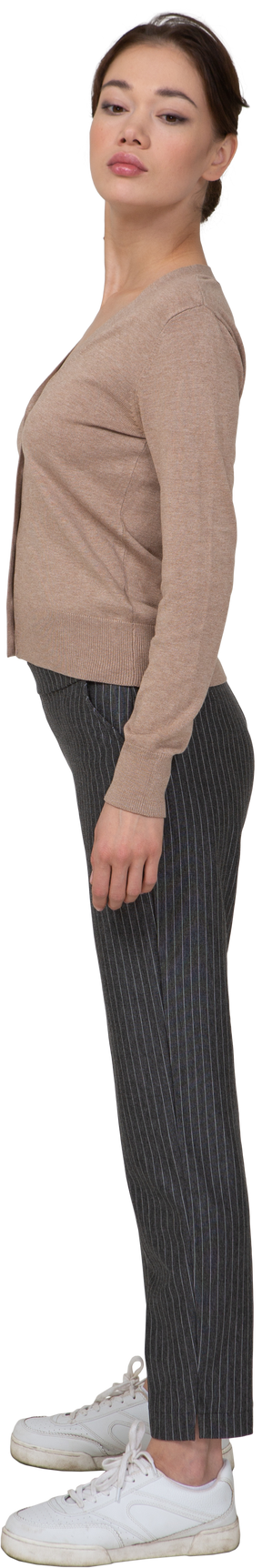 Vista lateral de una señorita en jersey y pantalones girando la cabeza